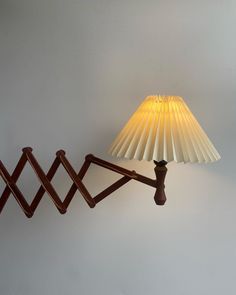 a lamp sitting on top of a wooden table next to a wall mounted light fixture