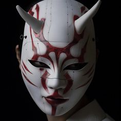 a person wearing a white mask with horns on it's head and red paint all over their face