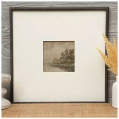 an old photo frame sitting on top of a table next to a vase with flowers