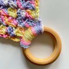 a wooden ring with multicolored crochet yarn on it sitting next to a white surface