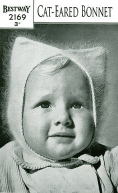 an old photo of a baby wearing a cat - eared bonnet and looking at the camera