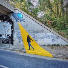 a woman walking past a yellow ramp with a space rocket painted on it's side