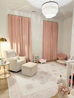 a baby's room with pink drapes, white furniture and a chandelier