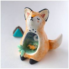 an orange and white cat figurine holding a fish in it's mouth