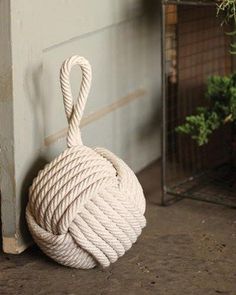 a white rope wrapped around a door handle on the ground next to a potted plant