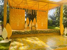 an outdoor wedding setup with yellow flowers and trees on the stage, surrounded by greenery