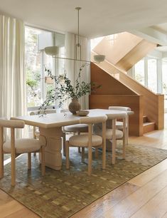 a dining room table and chairs in front of a stair case