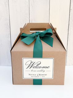 a welcome box with a green ribbon tied around the front and side, sitting on a white surface