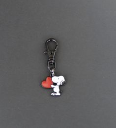 a keychain with a dog holding a heart on it's side, sitting on a gray surface