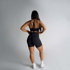 the back view of a woman in black shorts and sports bra top, with her hands on her hips