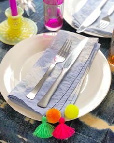 the table is set with silverware, napkins and pom - poms