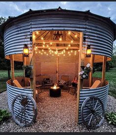 an outdoor fire pit made out of galvanige and metal barrels with lights on the roof