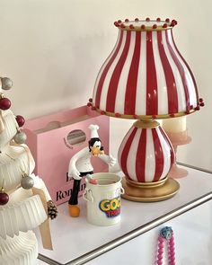 an assortment of christmas decorations on display in a store window with a red and white striped lamp next to it