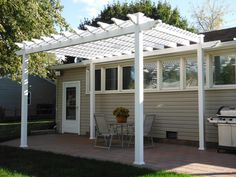 a white pergolan sitting on top of a patio next to a house