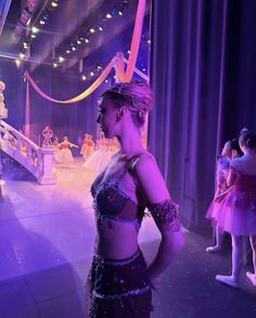 a woman standing in front of a stage wearing a purple outfit and headpieces