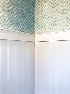 a white toilet sitting in a bathroom next to a blue wall and wooden paneling