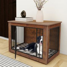 a black and white dog laying in a cage on the floor next to a table