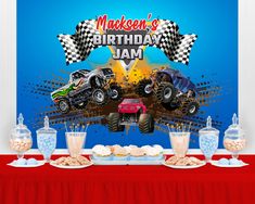 a birthday party with monster trucks and desserts on a red tableclothed table