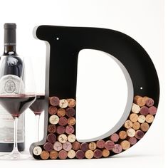 a bottle of wine next to a letter made out of wine corks and a glass of red wine