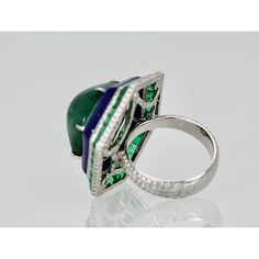 This is part of Chairish’s Fine Jewelry assortment.  Emerald Lapis Diamond Ring 18K  This modern Emerald Lapis and Diamond ring is absolutely exquisite and made in 18K white gold. There are 48 square Emeralds surrounding a Lapis band that circles this amazing 29 carat Sugarloaf Bullet Emerald. No details have been missed including the underside is set with Diamonds as are the shoulders of this setting. There are two rows of Diamonds above and below the the Emeralds Squares and the height of the Luxury 14k White Gold Green Diamond Ring, Luxury Green Diamond Ring In 14k White Gold, Luxury Emerald Rings With Polished Finish, Luxury Emerald Rings With Bezel Setting, Luxury Hallmarked Round Cut Emerald Ring, Luxury Emerald Rings Hallmarked, Luxury Platinum Halo Ring With Gemstone, Luxury Multi-stone Round Emerald Ring, Luxury Polished Emerald Ring