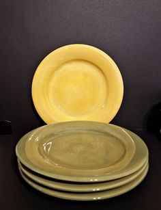 four yellow plates stacked on top of each other in front of a black tablecloth