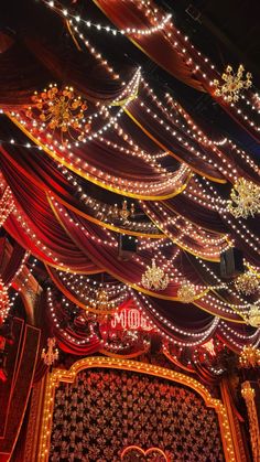 an elaborately decorated stage with lights and decorations on the ceiling is lit up at night