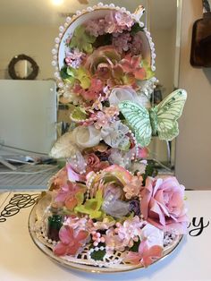 there is a cake decorated with flowers and butterflies on the top of it's stand