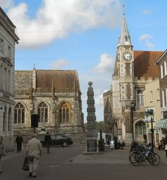 people are walking down the street in front of some old buildings and a clock tower