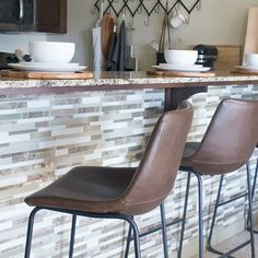 three bar stools sitting in front of a counter with plates and bowls on it