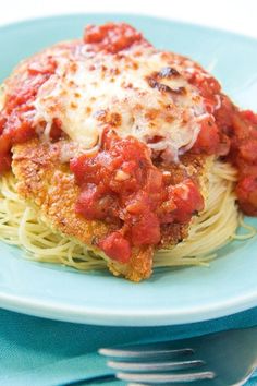 a blue plate topped with spaghetti and meat covered in marinara sauce next to a fork