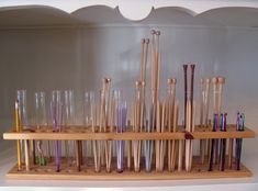 a wooden rack filled with lots of different colored glassware and toothbrushes on top of a shelf