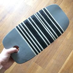 a person holding a skateboard on top of a hard wood floor covered in black and white stripes