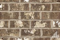 an old brick wall that has been painted brown and white with peeling paint on it