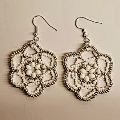 Intricate white and silvery seed beads made into earrings. White Metal Jewelry With Silver Beads, Nickel Free White Drop Earrings, Nickel-free White Drop Earrings, Handmade White Metal Earrings, Silver Beaded Earrings With Bead Caps For Gift, White Metal Chandelier Earrings For Pierced Ears, Nickel-free White Bohemian Chandelier Earrings, Handmade White Dangle Crystal Earrings, White Crystal Drop Earrings With Ear Wire