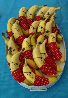 a bunch of bananas with faces on them in a bowl sitting on a blue table cloth