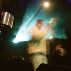 a blurry photo of a man on stage with lights behind him and people in the background