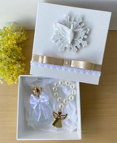 a white box with some pearls and other items in it next to a yellow flower