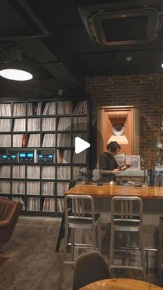 a man sitting at a table in front of a book shelf filled with books and cds