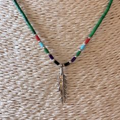 a necklace with a feather and beads on it