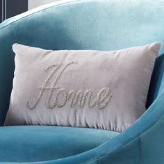 a blue chair with a silver pillow that says home on it and the word home written in cursive font