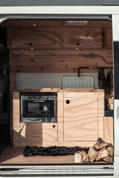 the interior of a camper van with its doors open and wood stacked in front