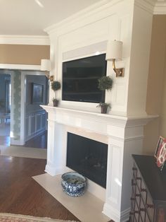 a living room with a fireplace and tv mounted on the wall above it's mantle