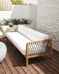 a white couch sitting on top of a wooden floor next to a potted plant