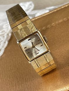 Elegant 1960's Vintage Japanese Art Deco small ladies 18 k gold plated Wristwatch Seiko Rainbow. Japanese Vintage ladies square mechanical watch with clear light golden color dial and golden color clock hands. Very exquisite 1960's Vintage Japanese ladies wristwatch Seiko. Collectible Japanese mechanical watch in excellent condition with 18k gold filled stainless steel bracelet top. An accent that would make every woman look stunning. Amazing present for vintage watch lovers. Wristwatch Ladies gift. Dress watch. Cocktail watch. Pre-owned. The item has been used previously. It may have some signs of cosmetic wear but is fully operational and functions as intended. Checked and serviced. Exceptional gift for the loved one. It is a striking looking watch with no visible defects (please, see th Vintage Gold Cocktail Watch, Retro Rectangular Watches For Formal Occasions, Retro Rectangular Formal Watches, Retro Gold Watch With Rectangular Dial, Retro Gold Watches With Rectangular Dial, Retro Yellow Gold Watch As Gift, Retro Yellow Gold Watch For Gift, Timeless Gold Square Watch, Retro Gold Watch With Polished Finish