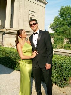 a man in a tuxedo standing next to a woman in a green dress