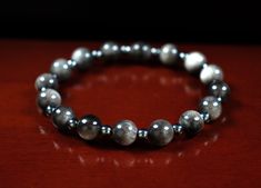 a close up of a bracelet on a wooden surface with beads and silver metal balls