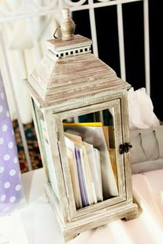 a small white lantern sitting on top of a bed next to a pile of books