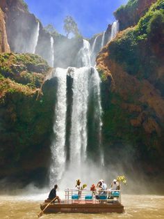 people are sitting on a raft in front of a waterfall with water falling from it