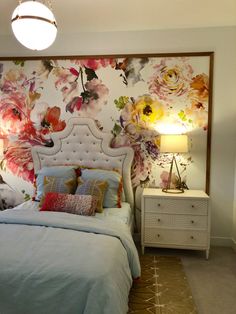 a bedroom with floral wallpaper and a white bed in front of a night stand