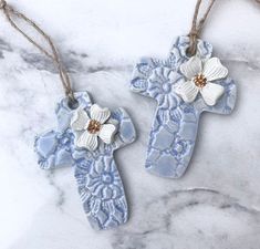 two blue and white ceramic cross ornaments on a marble counter top with twine of twine